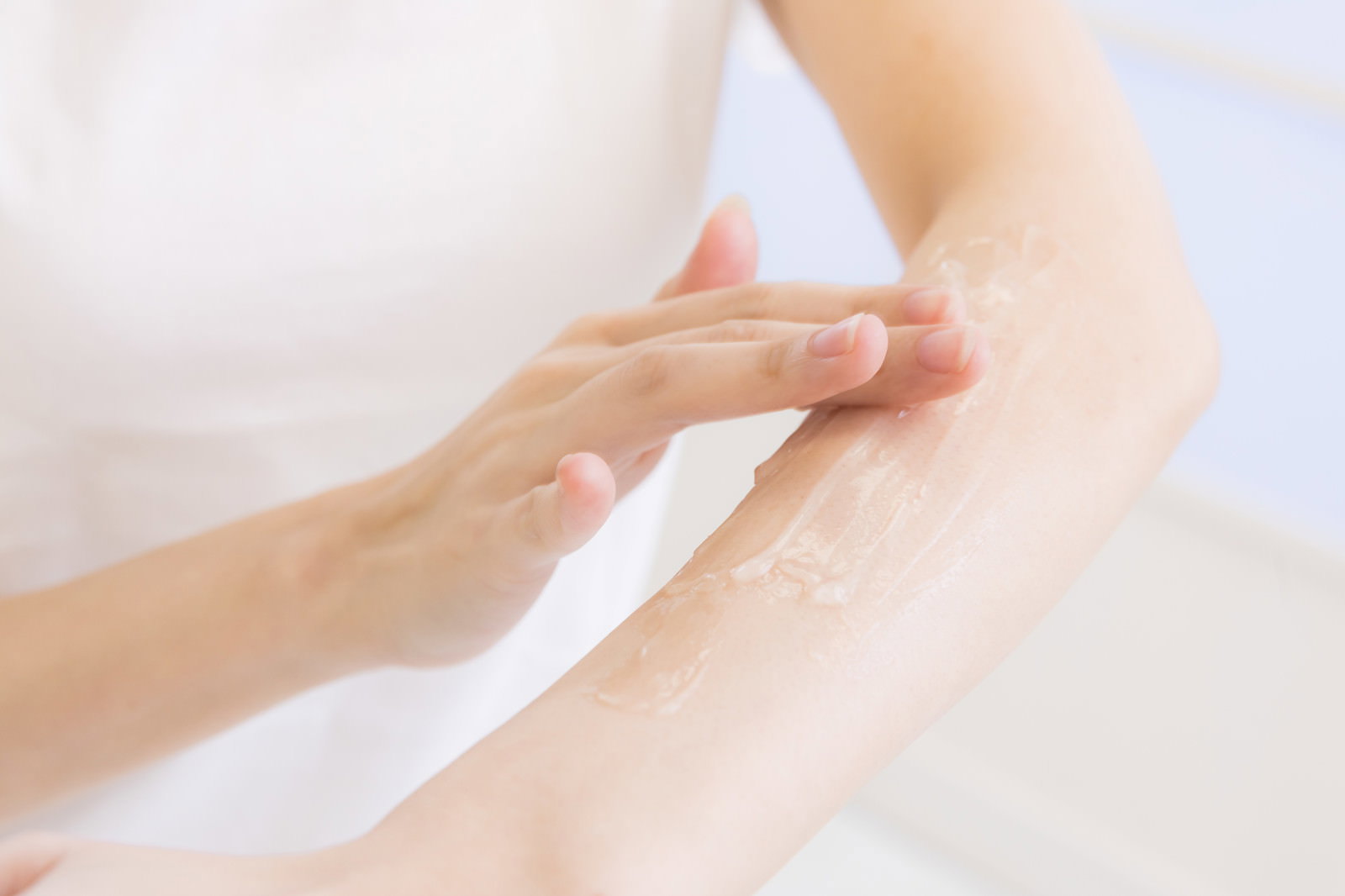 腕に透明なジェルを手で塗布している女性の手元