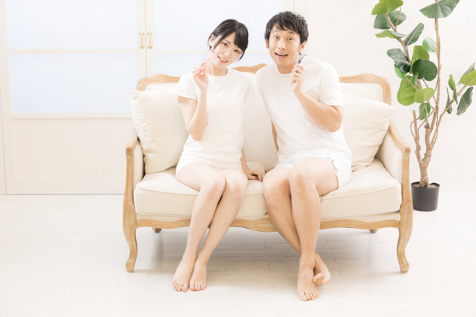 白いソファに座る男女のカップルが並んでいる。白い室内でカウンセリングを受ける様子［モデル：緋真煉 大川竜弥］