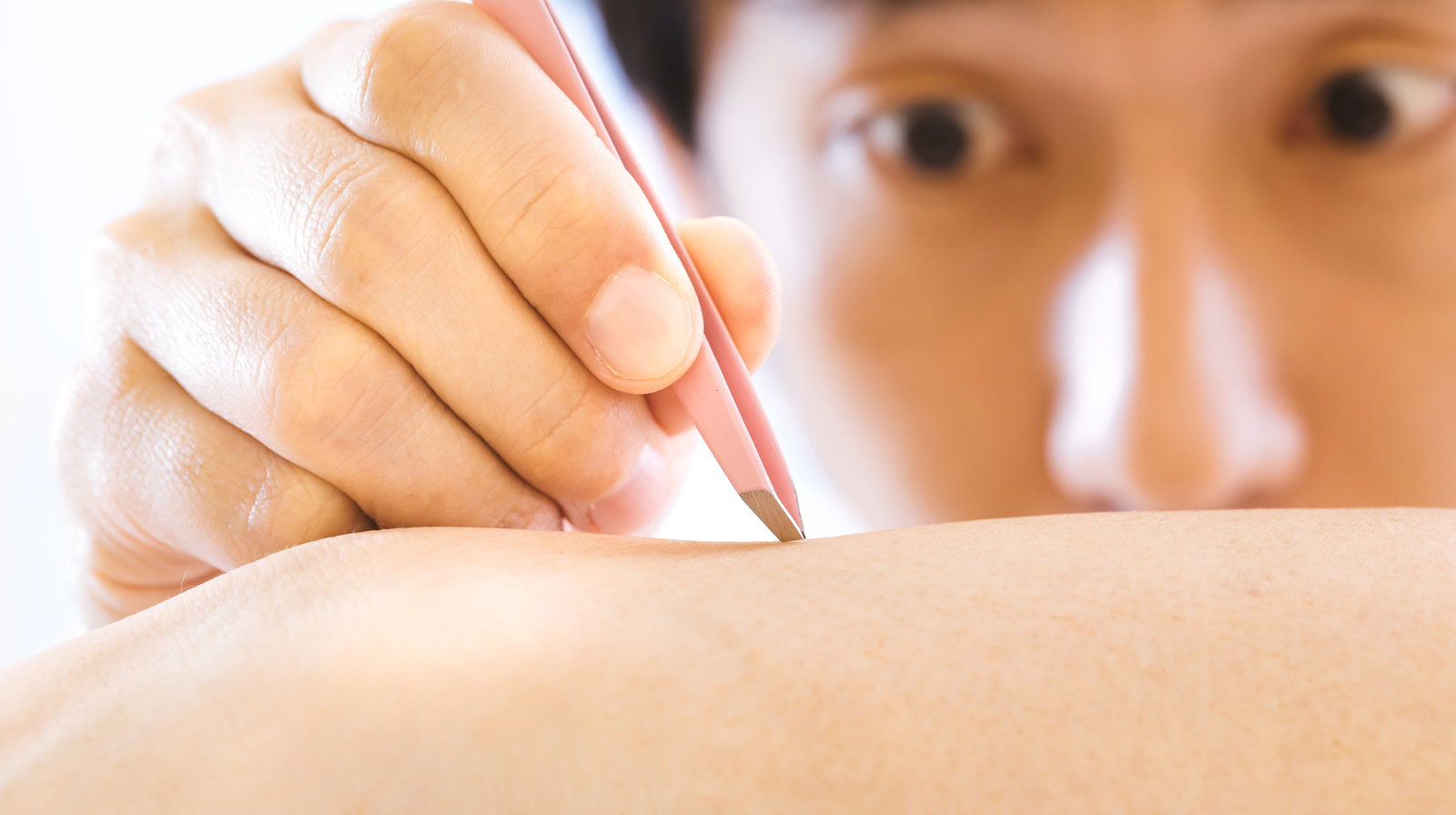 毛抜きを使ってムダ毛を一本ずつ処理している手元の様子［モデル：大川竜弥］