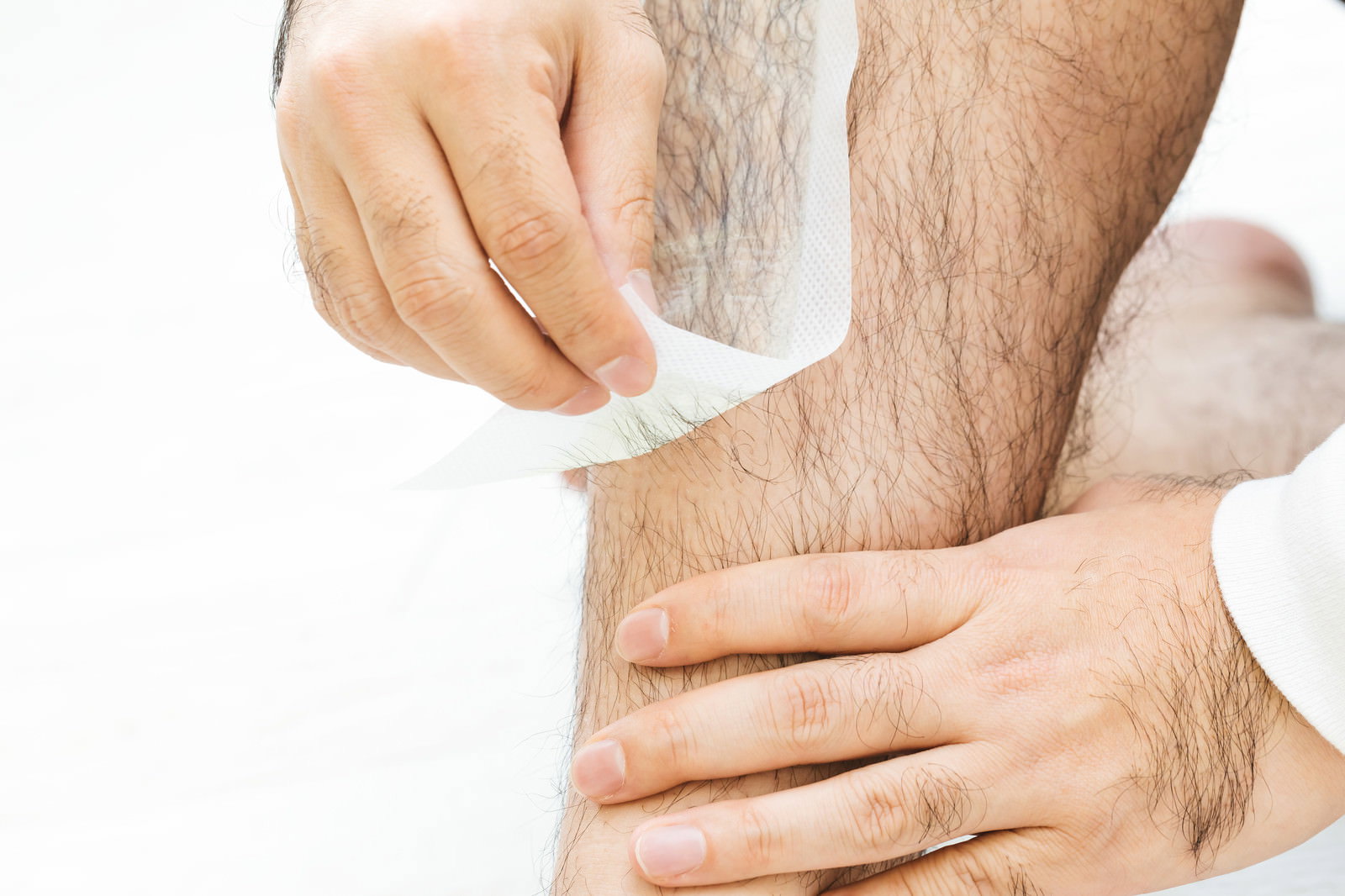 脱毛シートを使ってすね毛を処理する男性の手の様子