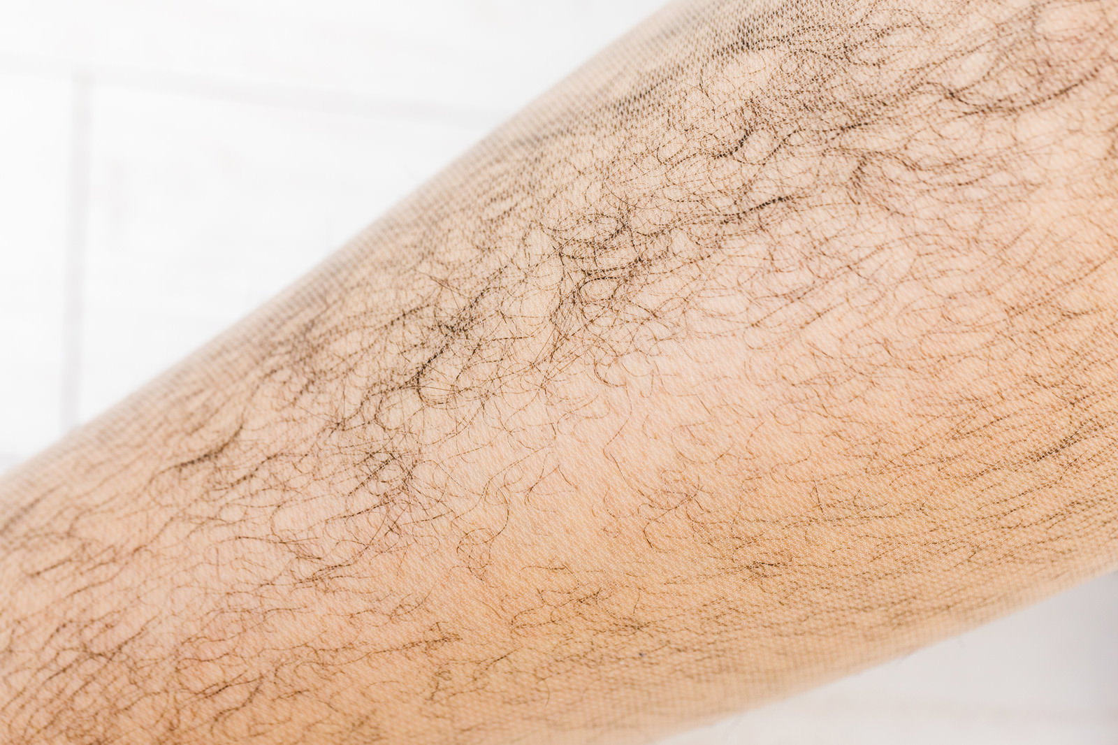 ストッキングを履いた足のすね部分で剛毛が透けて見える