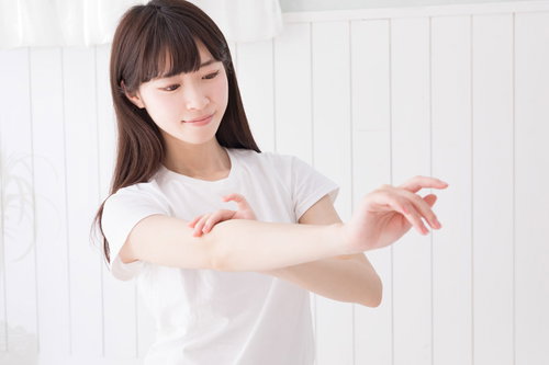 白いトップスで腕の産毛をチェック中の女性