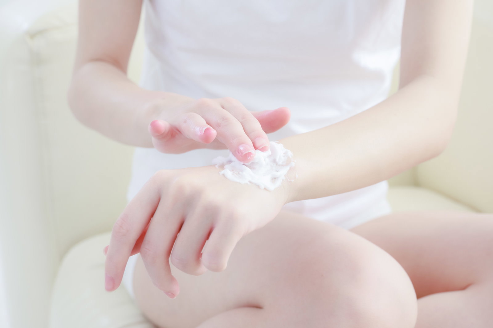 白いクリームを指で腕の甲に塗る女性の手元［モデル：川子芹菜］