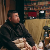 汚部屋でテレビを見る無精髭の太った男性のライフスタイルの写真