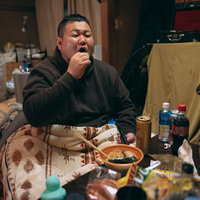 汚部屋でマイクを握る太った男性の暴飲暴食な生活の写真