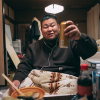リモート飲みでビールとラーメンで乾杯する男性の写真