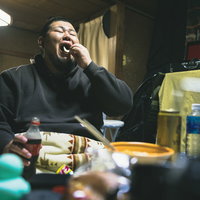 大きな口でポテトチップスを頬張る無精髭の男性の写真