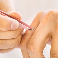 指毛をピンセット（毛抜き）で抜く手元のクローズアップの写真