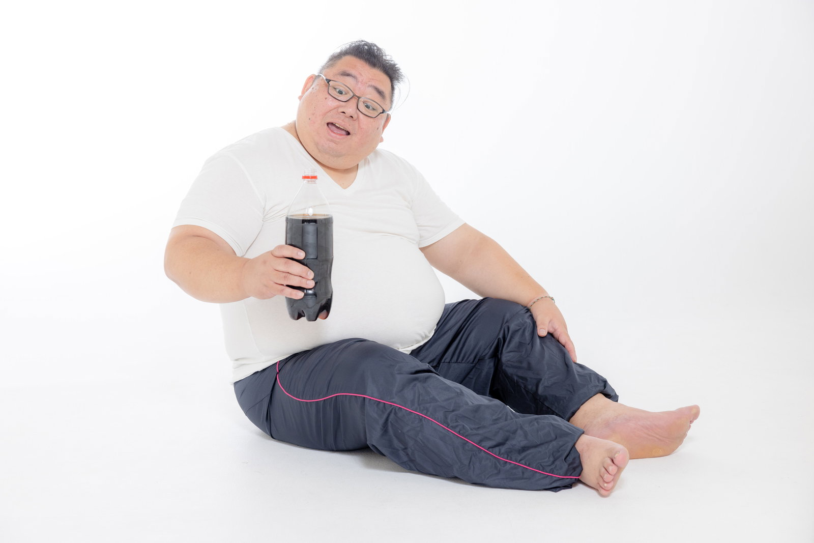 炭酸ジュースを持ち床に座る体格の大きな男性［モデル：ダルマ親方］