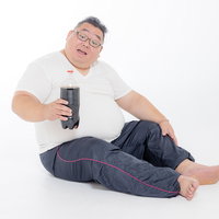炭酸ジュースを片手に座り込む膨よかな男性の写真
