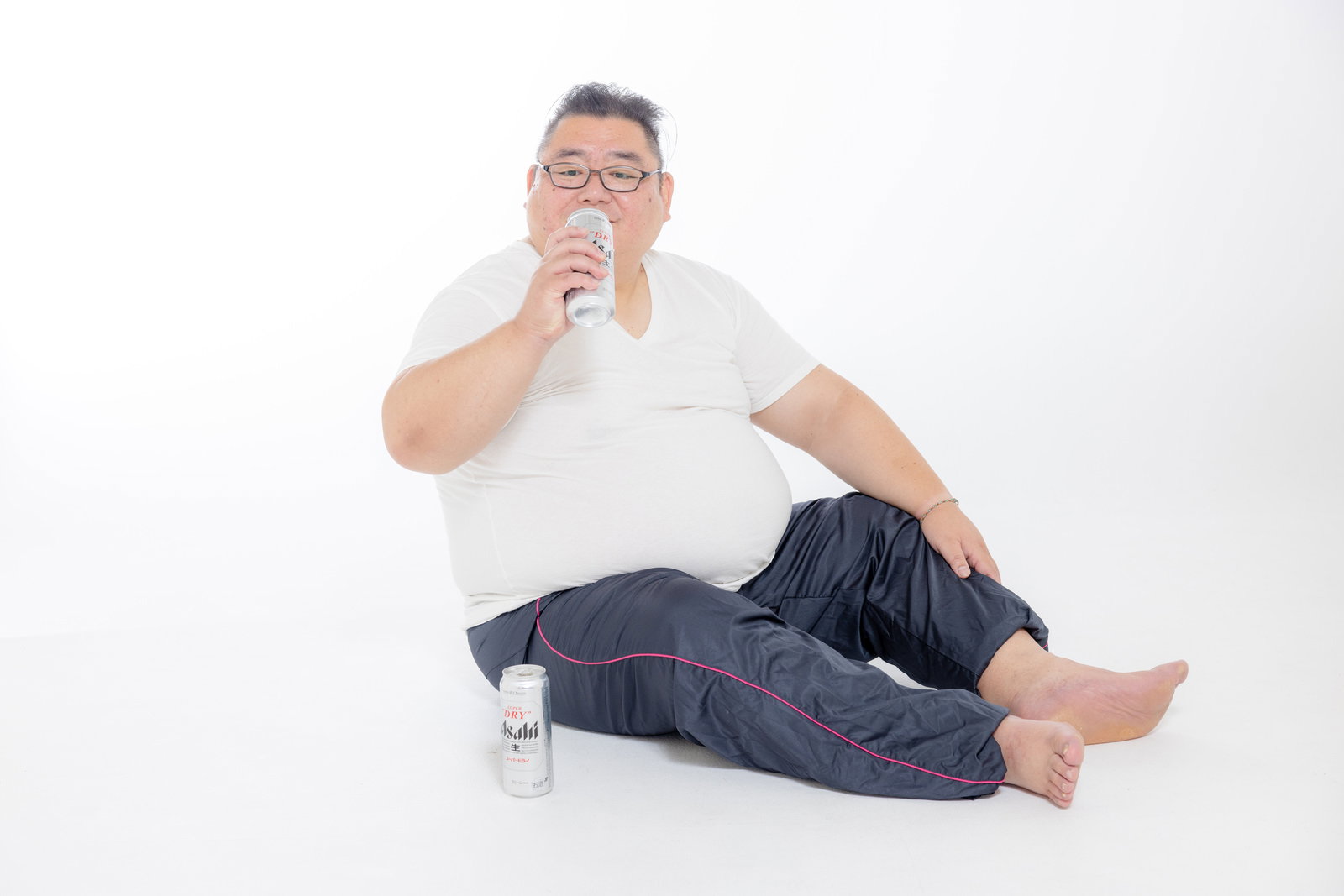 床に座り缶ビールを飲む、ぽっちゃりした体型の男性［モデル：ダルマ親方］
