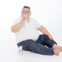 座り込んで缶ビールを飲む膨よかな男性の生活習慣の写真