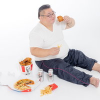ファーストフードとビールで暴飲暴食する肥満男性の写真