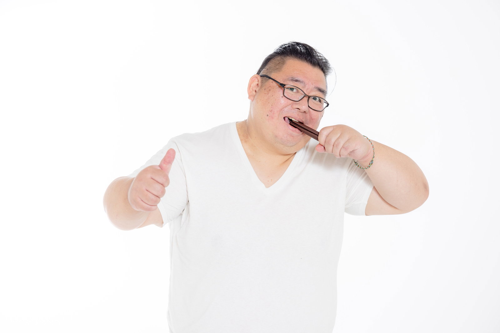 ポッキーを口に含んで貪り食う眼鏡姿の男性がカメラに向かって親指を立てている［モデル：ダルマ親方］