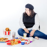 ファーストフードに囲まれて横座りする女性の写真