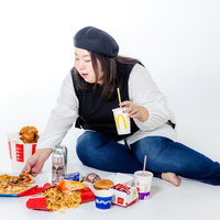 横座りしてジャンクフードを食べる女性、ファーストフードの写真