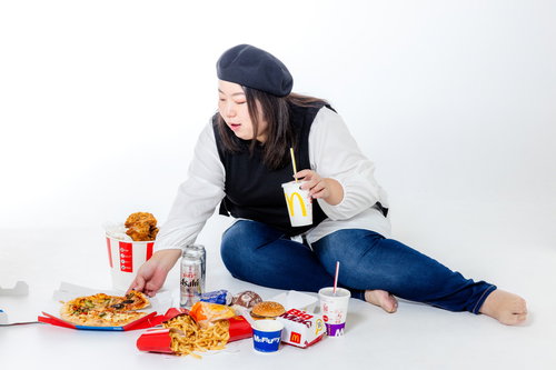 横座りしてジャンクフードを食べる女性、ファーストフード