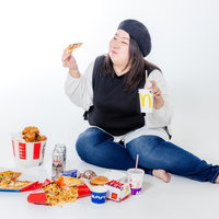 ファーストフードを食べる横座りの女性、肥満体の写真