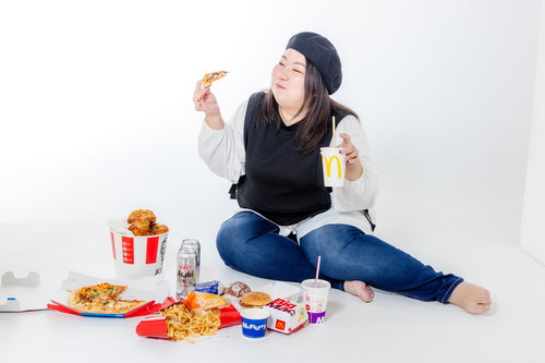 ファーストフードを食べる横座りの女性、肥満体