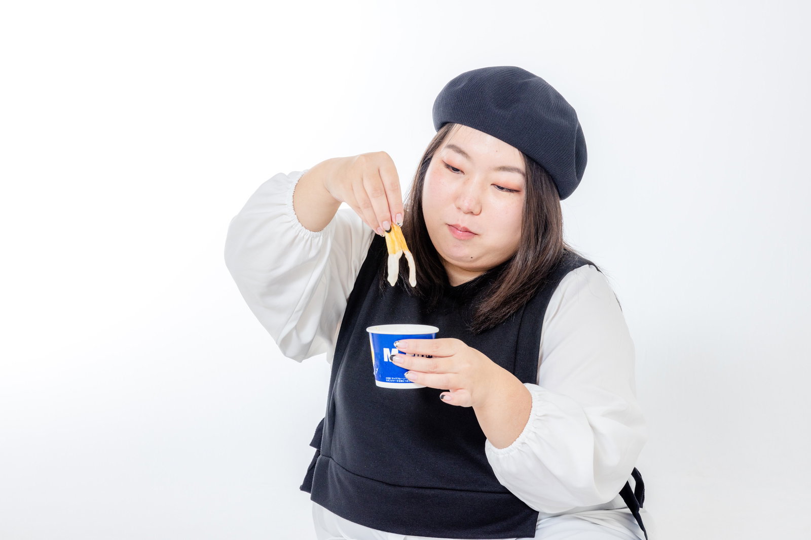 アイスにポテトをつけて食べる女性がそっと下を向いて食べている［モデル：KANA］