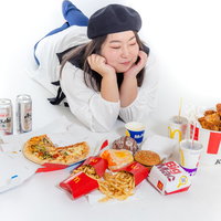 ジャンクフードに囲まれた女性の食べ物の写真