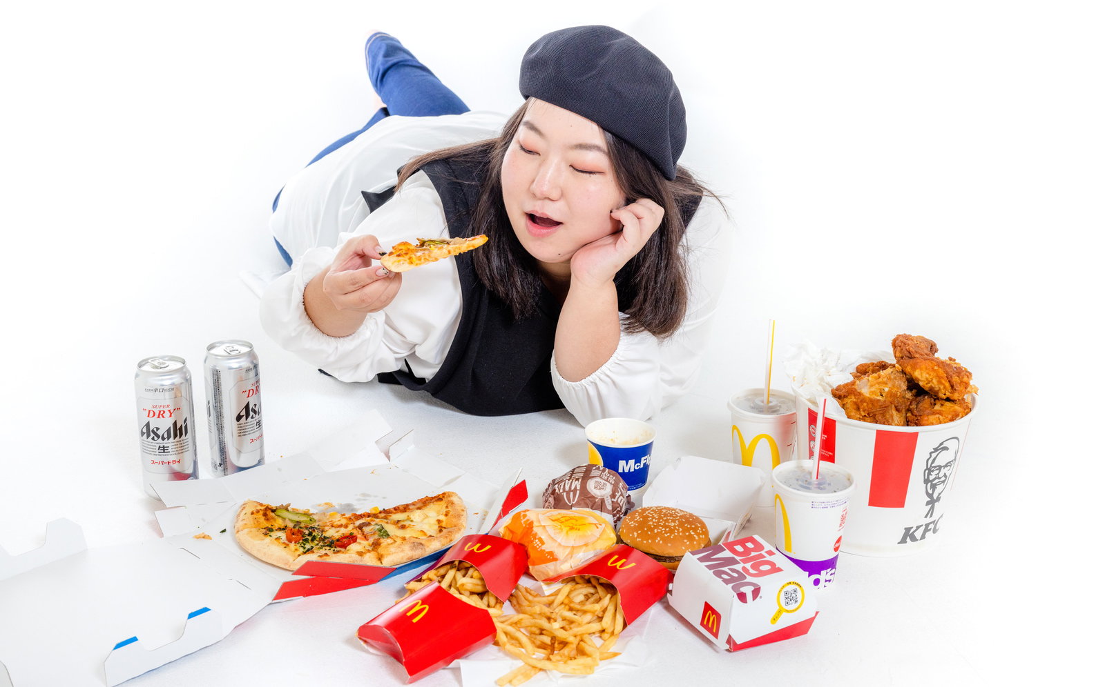 白背景で黒ベレー帽をかぶった女性がジャンクフードを頬杖ついて食べている様子［モデル：KANA］