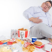 ファストフードの食べ過ぎで苦しむ太った男性の写真