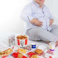 出前で大量注文して食べ過ぎた男性、ファーストフードに囲まれて暴飲暴食の写真