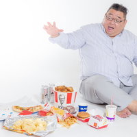 頼み過ぎたファーストフードに驚く膨よかな男性の写真