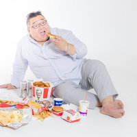 ジャンクフードを食べるずぼらな男性、暴飲暴食の食生活の写真