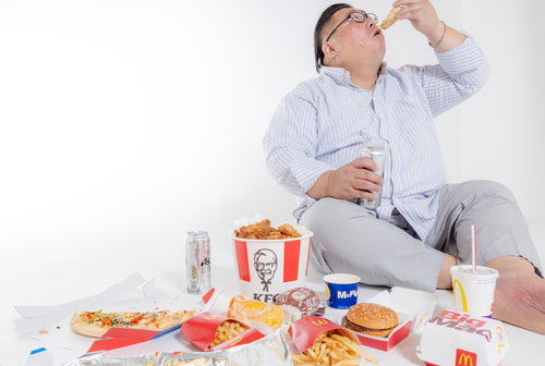 ダラダラと暴飲暴食するファーストフードに囲まれた膨よかな男性