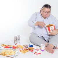 ケンタッキーを食べながら暴飲暴食する男性の写真