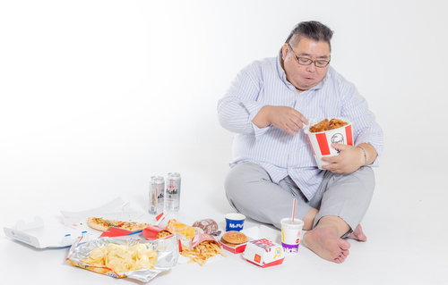 ケンタッキーを食べながら暴飲暴食する男性