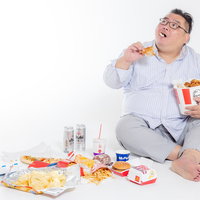 ケンタッキーフライドチキンを暴食するメガネの男性、ビールで流し込むの写真