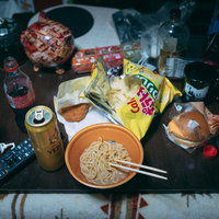 散らかった部屋で食べる孤独飯、テーブルに広がるビールとラーメンの写真