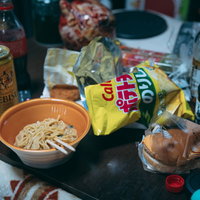 散乱したゴミ部屋で食べるカップラーメンとお酒の夕食の写真