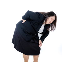 腰を痛めて身体を丸める膨よかな女性会社員のオフィスワークの写真