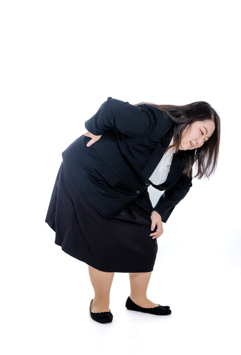 紺色のスーツを着た女性が腰に手を当てて前かがみになっている［モデル：KANA］