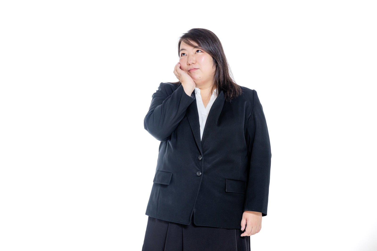 スーツを着た体が大きめな女性が頭を抱えて悩んでいる［モデル：KANA］