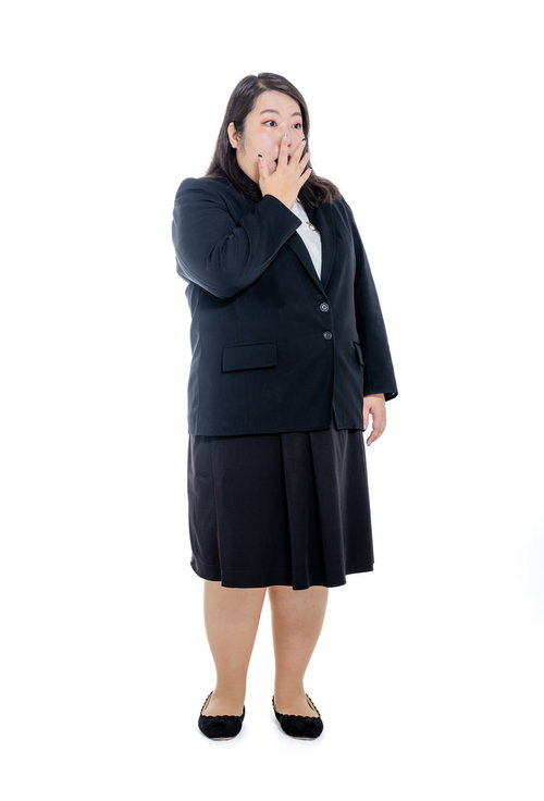 右手で口を押さえて驚く肥満体型のスーツ姿女性