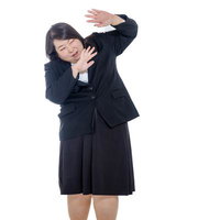 両手で防御ポーズを取るぽっちゃりビジネスウーマンの写真