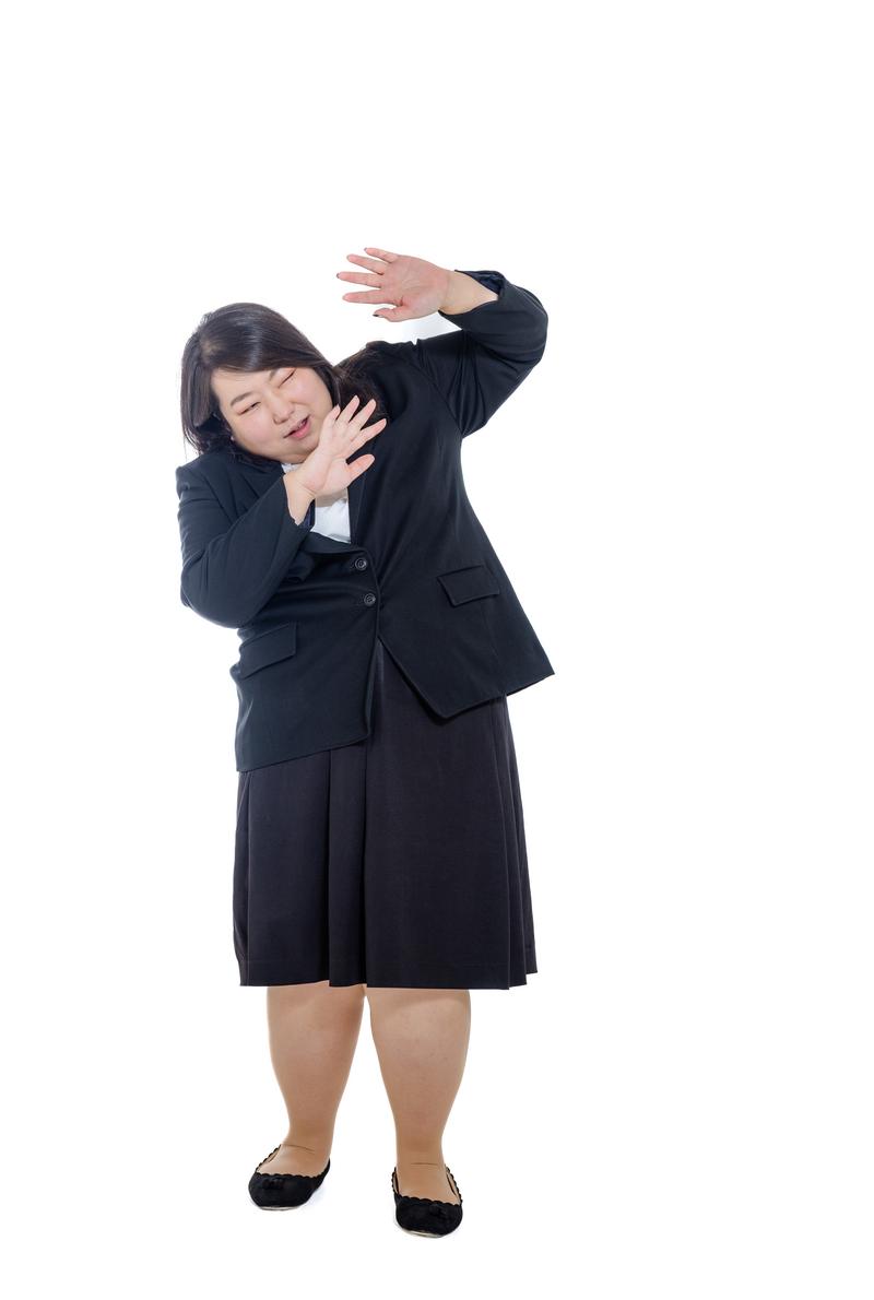 A woman in a black suit making a defensive pose with both hands