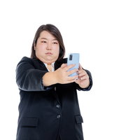 スマホで自撮りする二重あご女子のビジネススーツ姿の写真