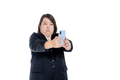 スマホで自撮りする二重あご女子のビジネススーツ姿