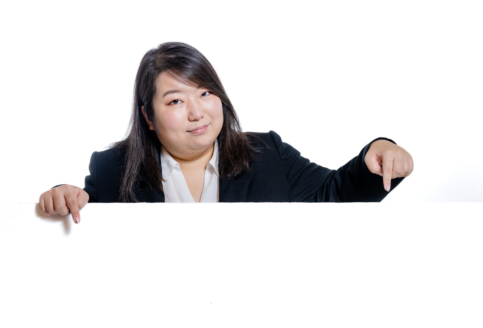 黒いスーツを着た女性が両手で下を指差している［モデル：KANA］