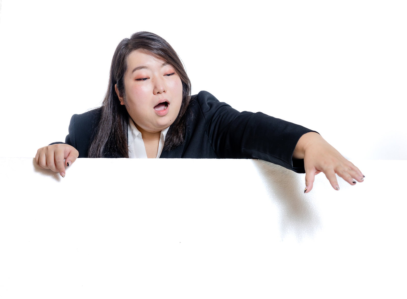 塀越しに手を伸ばして掴もうとする黒いジャケット姿の女性会社員［モデル：KANA］