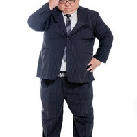 はち切れそうなスーツ姿で頭を掻く困惑する会社員の男性の写真