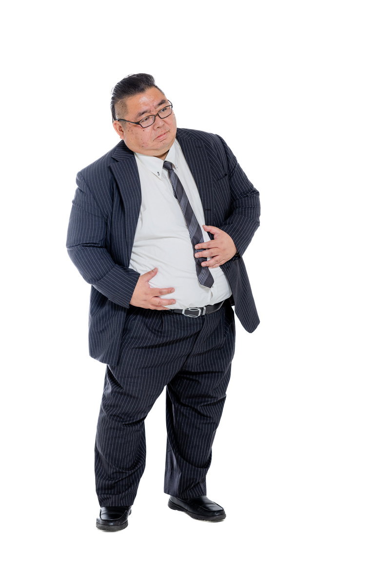 紺色のストライプスーツ姿で、両手でお腹をさする膨よかな男性［モデル：ダルマ親方］