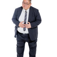 胃痛を訴えてお腹を押さえるスーツ着用の男性の写真