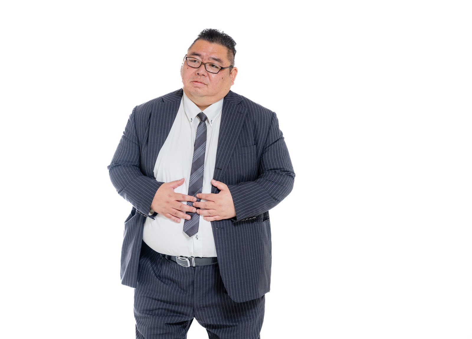 お腹の痛みを訴える膨よかなスーツ姿の男性［モデル：ダルマ親方］